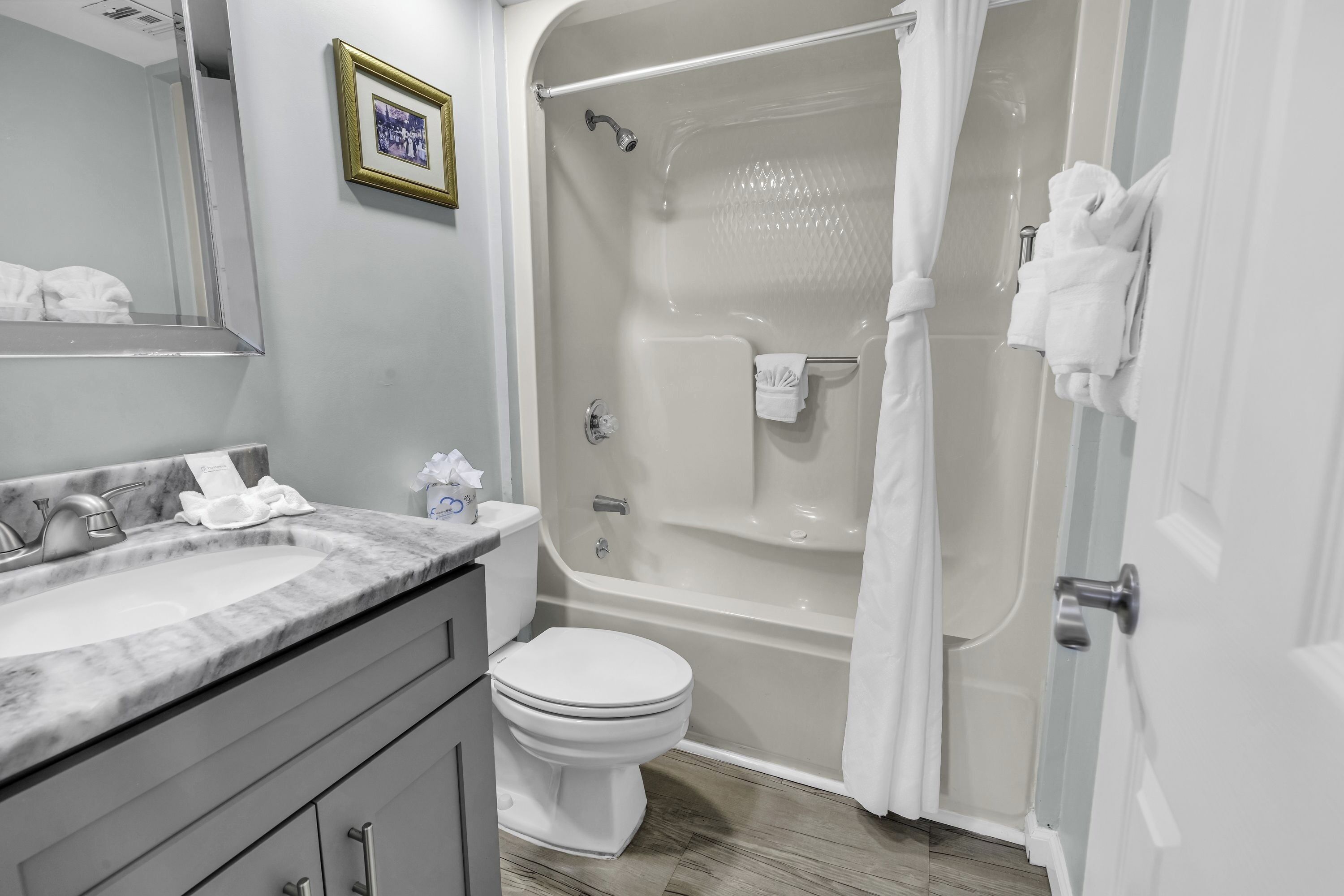 Un baño con lavamanos de mármol, inodoro y ducha a ras de suelo con puerta de vidrio.