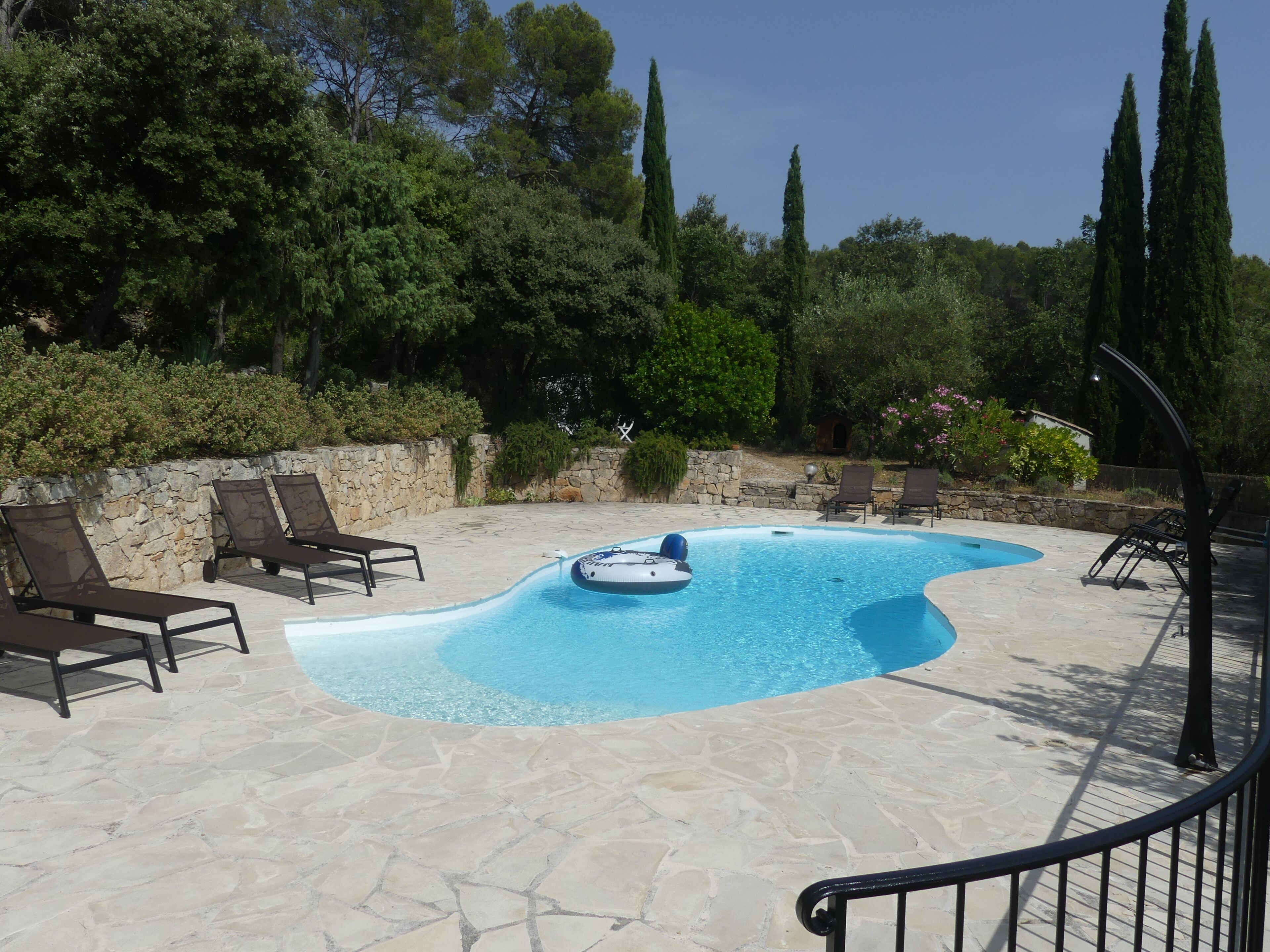 Una piscina con sillas de descanso y un muro de piedra.
