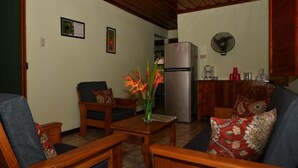 A cozy living room with wooden furniture, a refrigerator, and a fan. - Hacienda Barú Lodge (Savegre)