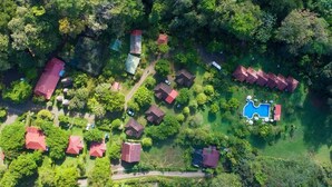 An aerial view of a residential area with multiple houses, a swimming pool, and surrounding greenery. - Hacienda Barú Lodge (Savegre)