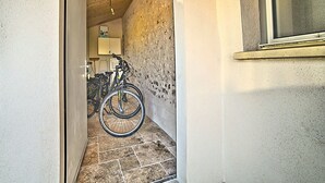 A narrow hallway with a wooden ceiling, a bicycle leaning against the wall, and a window on the right.