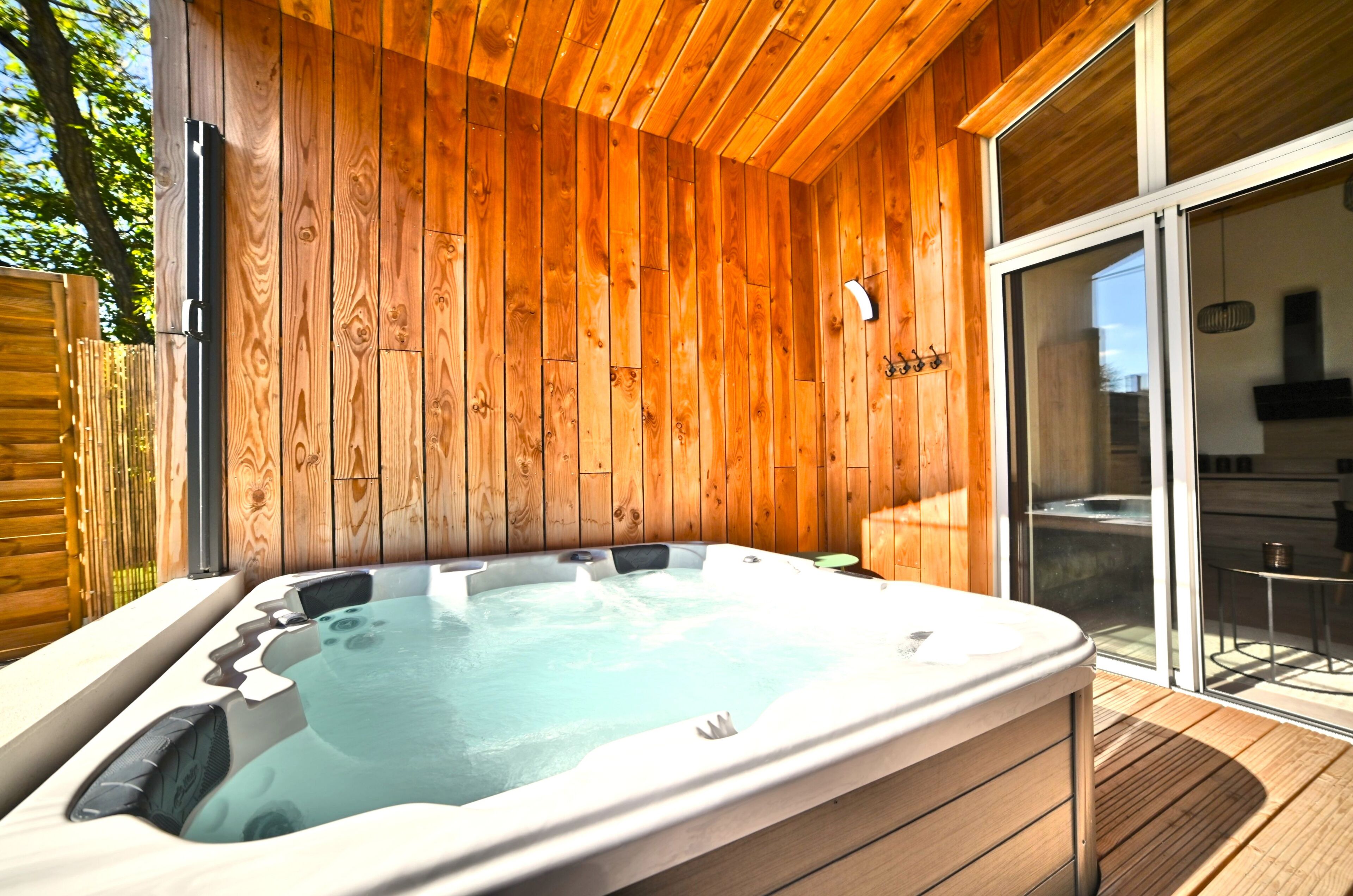 A hot tub in a wooden cabin with a sliding glass door leading to a patio.