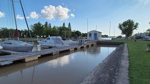 A marina with boats docked, a grassy area, and a small building.