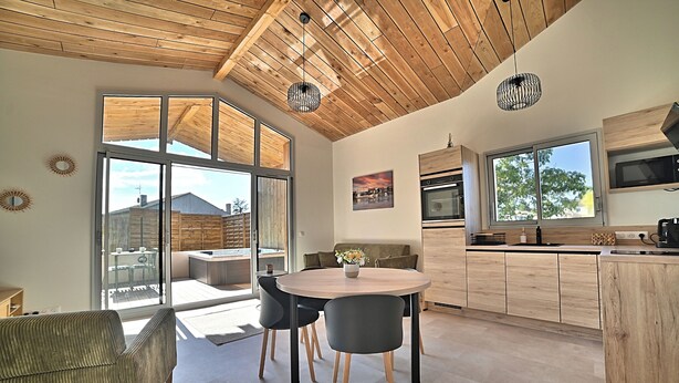A modern kitchen with wooden cabinets, a dining area with a round table and chairs, and a large sliding glass door leading to an outdoor patio.