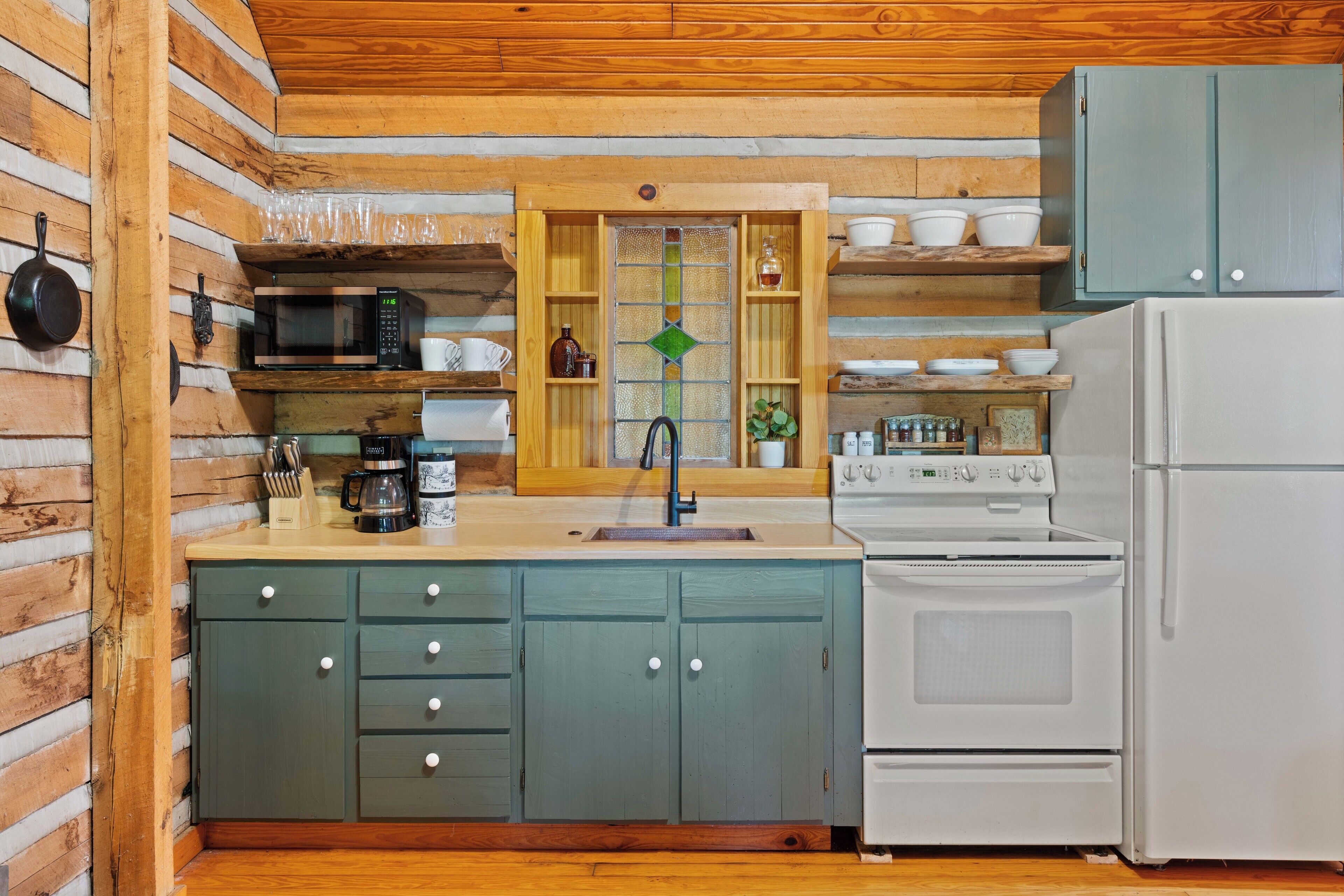 A compact kitchen with a microwave, stove, and sink.