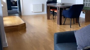 Un salon moderne avec un plancher en bois, un canapé bleu foncé et un coin repas comprenant une table et des chaises.
