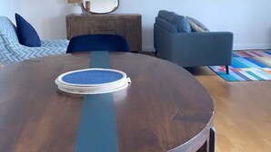 Une table de salle à manger ronde en bois, avec une bande centrale bleue, entourée de chaises bleues recouvertes de tissu.