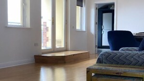 Une pièce avec un plancher en bois, une chaise bleue et un coussin à motifs.