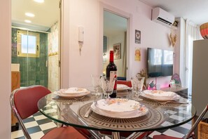 A dining area with a glass table, chairs, and a bottle of wine.