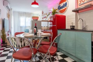 A retro-themed kitchen with a red refrigerator, a dining table with red chairs, and a neon sign for 'Gulf Las Vegas.' - American Dinner - 2BR / Wifi / Smart TV 55` / Pool (Salou)