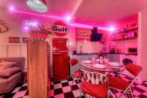 A retro-themed kitchen with a red refrigerator, a neon 'hello' sign, and a 'Gulf' sign. - American Dinner - 2BR / Wifi / Smart TV 55` / Pool (Salou)