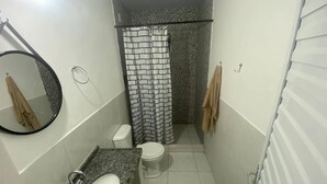 Une petite salle de bain avec un lavabo blanc, des toilettes et un rideau de douche.