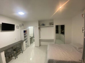 Cozy retreat with a bed, desk, and TV, set amidst a clean and minimalist design.