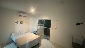 Une chambre à coucher avec un lit, une fenêtre et une porte donnant sur une autre pièce.