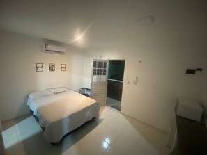 Relax in a serene bedroom with a large bed, bedside table, and window offering a view of the outside.