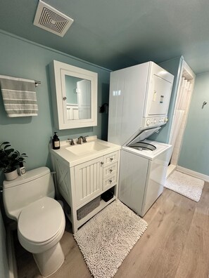 Un baño con inodoro, lavamanos, armario y zona de ducha.