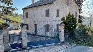 A two-story stone building with a gated entrance, a chimney, and a satellite dish.