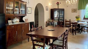 A dining area with a wooden table and chairs, a chandelier, and a cabinet with glass doors.