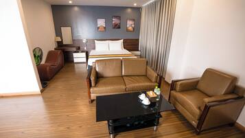 Quarto de hotel com cama, dois sofás, mesa de centro, escrivaninha e uma cadeira.