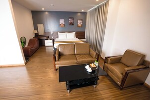 Quarto de hotel com cama, dois sofás, mesa de centro, escrivaninha e uma cadeira.