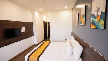 A hotel room with a bed, a flat-screen TV mounted on the wall, and artwork on the wall.