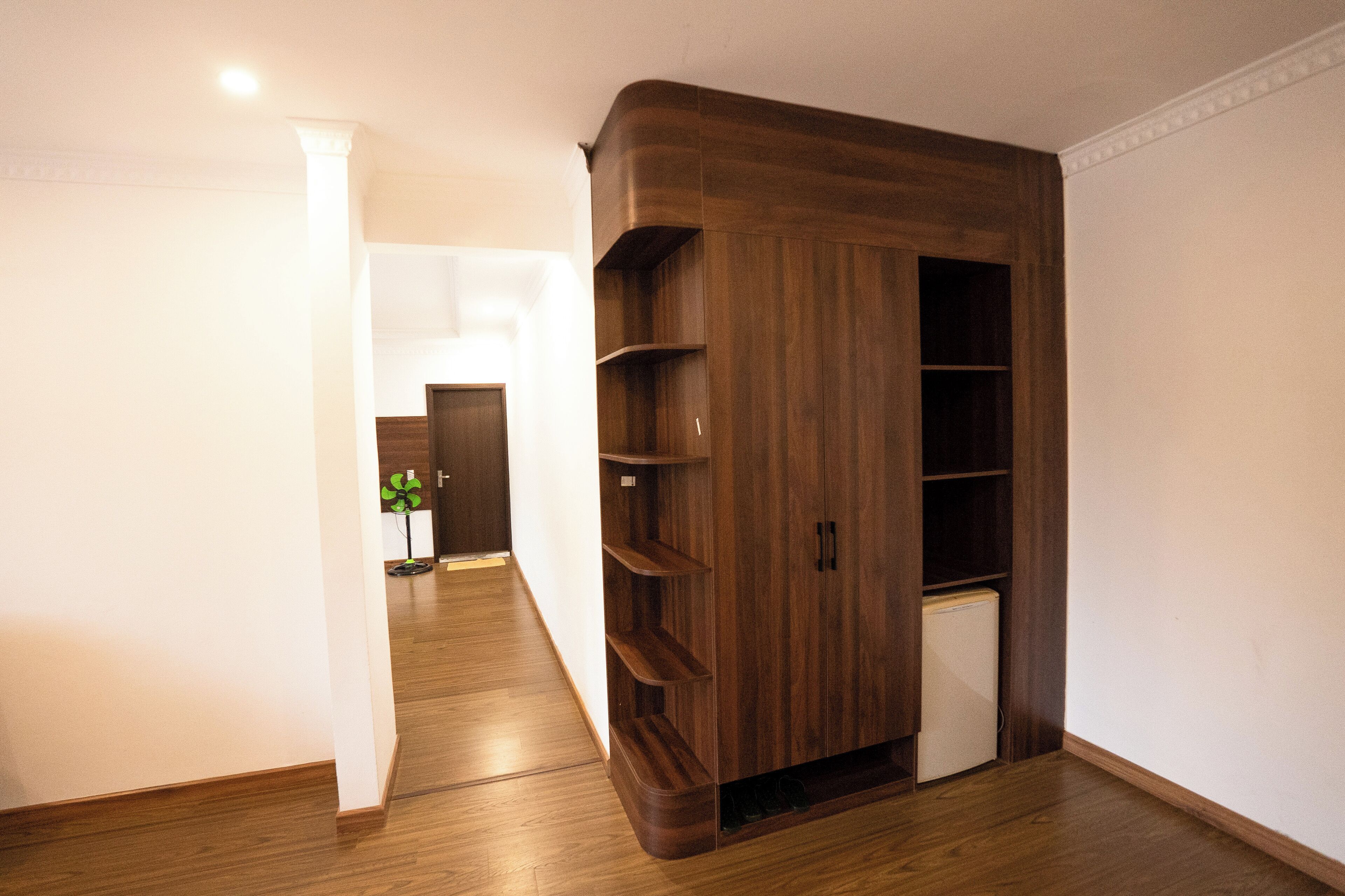 A hallway with a wooden wardrobe, a radiator, and a white door.