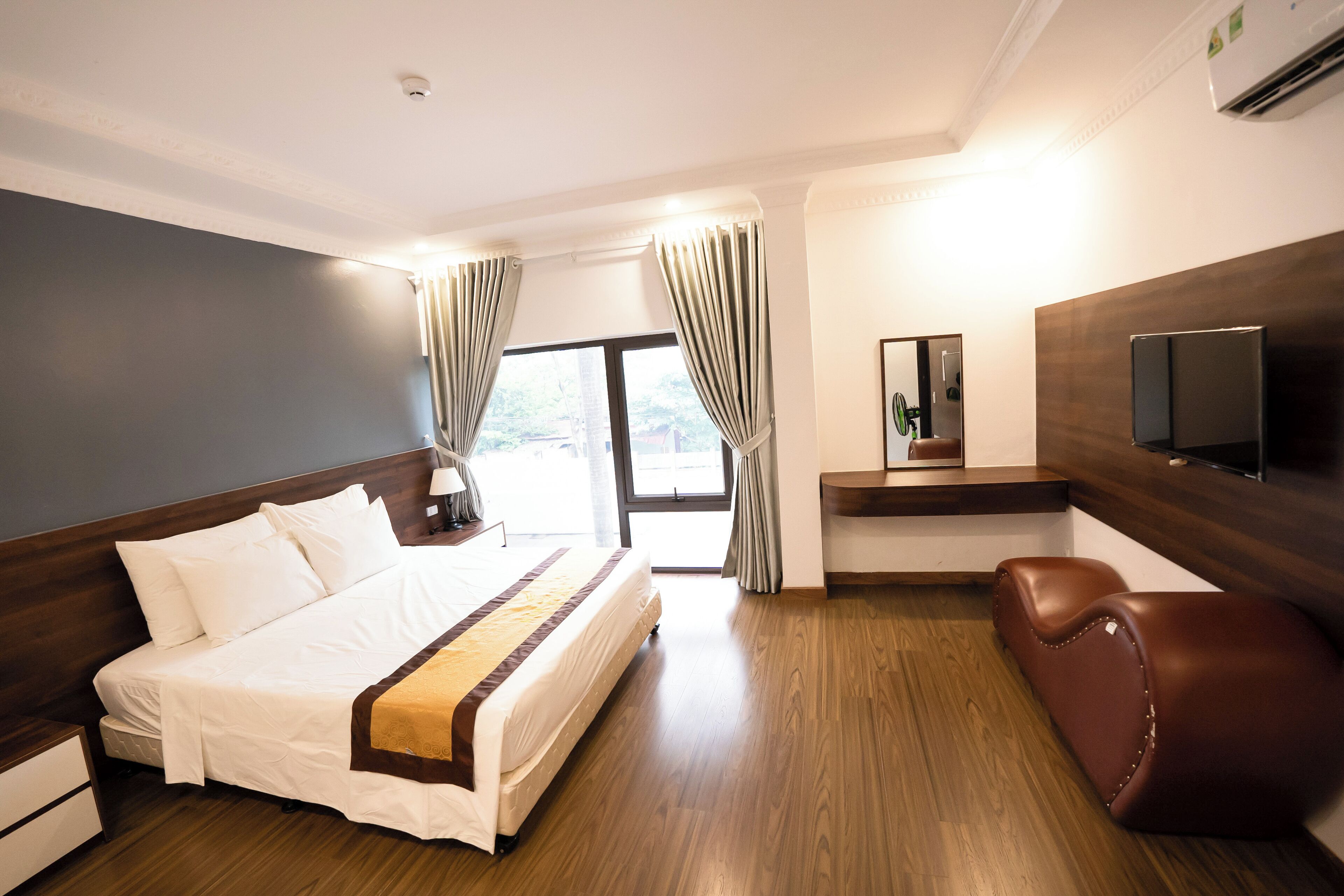 Una camera d'albergo con un letto grande, una scrivania, una televisione e una finestra con tende.