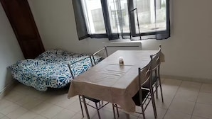 A dining area with a table and chairs, a patterned sofa, and a window with curtains. - Charming cottage in the heart of Saintes (Saintes)