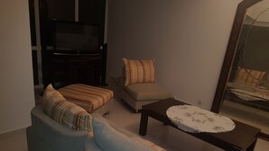 A living room with a sofa, a small table, and a television.