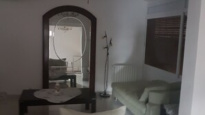 A modern living room with a sofa, a coffee table, a side table, a mirror, and a radiator.