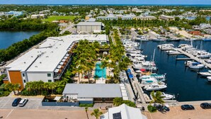 A marina with boats docked, a swimming pool, and a building with a flat roof. - Sailboat Stay • Marina Pools • Sleeps 4 • Stock Island, Key West (Key West)