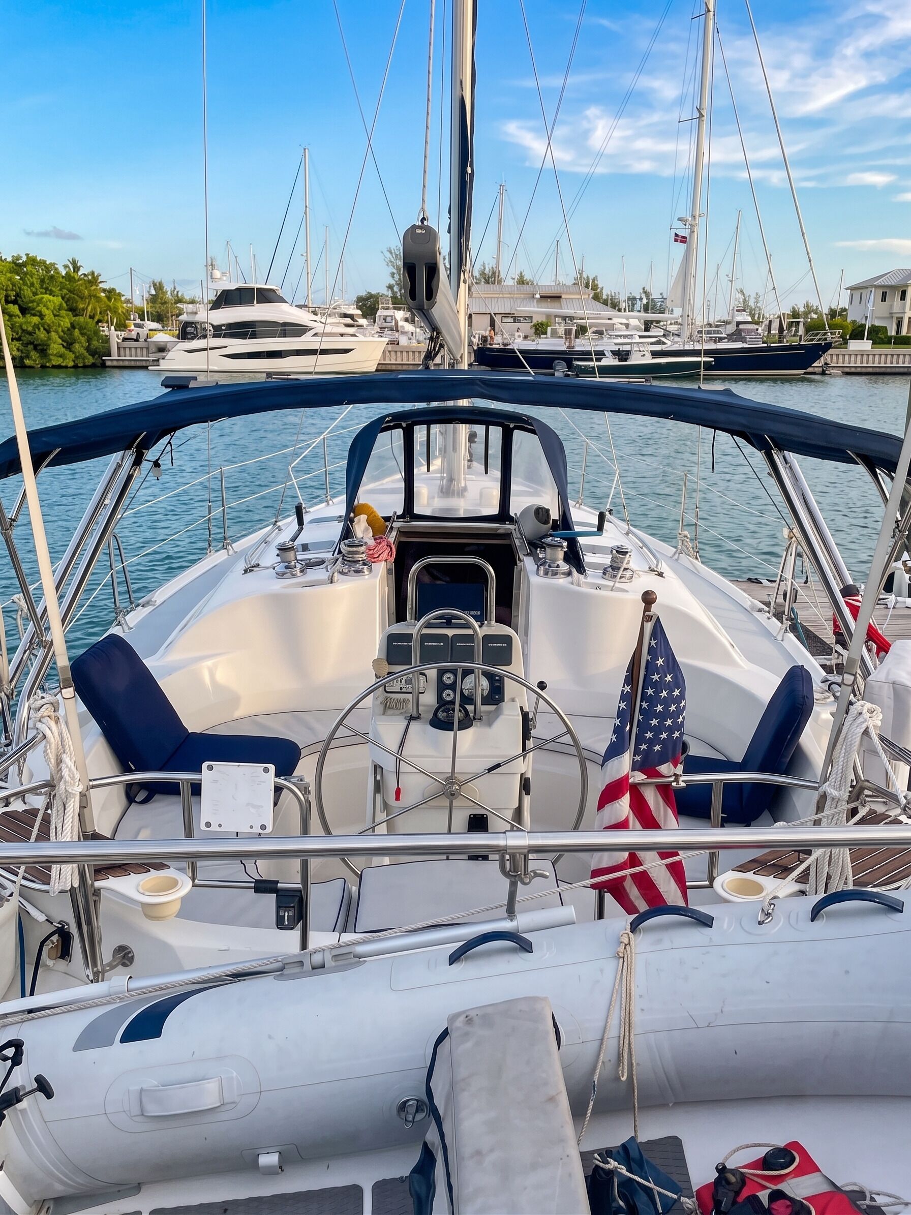 A boat's deck with a steering wheel, control panel, and American flag.