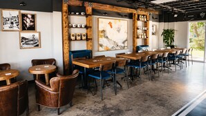 A modern cafe with wooden tables and chairs, framed pictures on the walls, and a large window with a view. - Sailboat Stay • Marina Pools • Sleeps 4 • Stock Island, Key West (Key West)