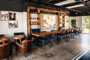 Un café moderne avec des tables et des chaises en bois, des tableaux encadrés aux murs et une grande fenêtre donnant sur un beau paysage.