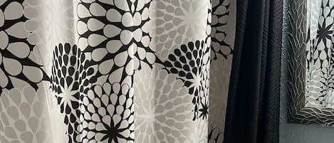 A bathroom with a shower curtain featuring a black and white floral pattern, a white sink, and a mirror above it.