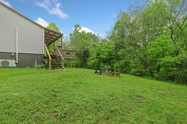 A backyard with a wooden deck, a grill, and a chair.