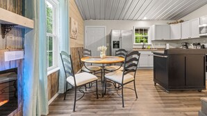Eine moderne Küche mit Holzboden, einem Essbereich mit rundem Tisch und Stühlen sowie einem großen Kühlschrank.
