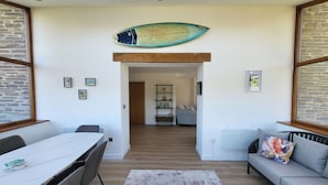 Una sala moderna con comedor, un sofá y una decoración con una tabla de surf.