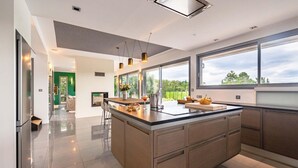 Una cocina moderna con una isla grande, ventanas amplias y vistas a zonas verdes.