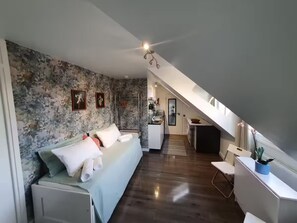 Experience the unique loft-style living area with a sofa, kitchenette, and sloped ceiling.