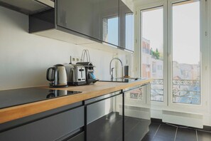 Cozinha moderna com bancada de madeira, armários pretos e vista da cidade por grandes janelas.