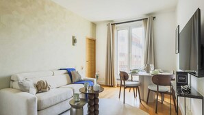 A modern living room with a sofa, coffee table, and dining area. - Charming Flat -1br-4p- Paris 17e (Paris)