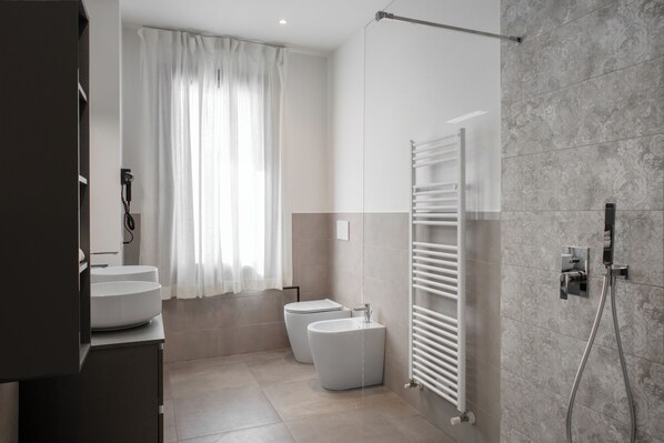 A modern bathroom with a large window, a shower, and a toilet.