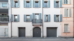 Un edificio de varios pisos con una entrada central, varias ventanas con contraventanas y balcones.