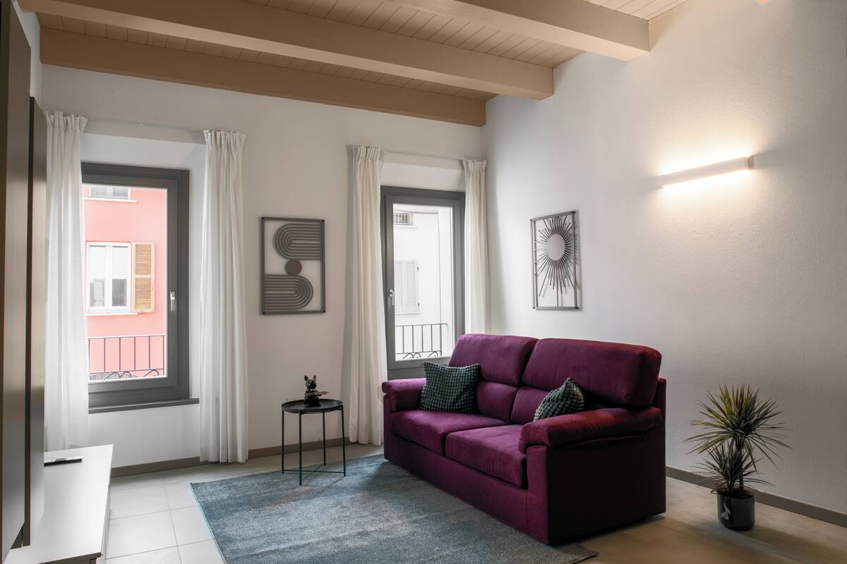 A living room with a red sofa, a small side table, and a potted plant.