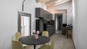 Una cocina moderna con armarios oscuros, una encimera negra y un comedor con una mesa redonda y sillas amarillas.