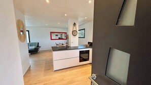 Een moderne keuken met een centraal eiland, een zithoek met een bank en een woonkamer met een bank en een televisie.
