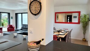 Een moderne keuken met een zwart aanrecht, een geweven mand met een fles, en een klok aan de muur.