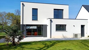 Een modern huis met twee verdiepingen, grote ramen en een plat dak.