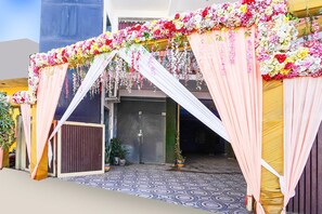 An entrance with a floral archway and draped curtains, leading to a building with a patterned floor.